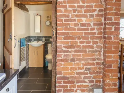 a bathroom with a brick wall and a sink at Top Farm Cottage in Oswestry