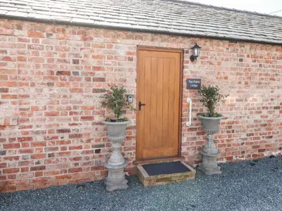a brick building with a wooden door and two potted plants at Top Farm Lodge in Oswestry