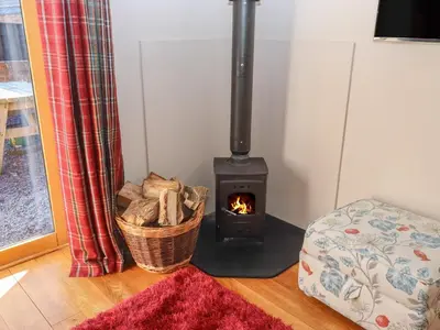a wood burning stove in a room with a couch at Top Farm Lodge in Oswestry