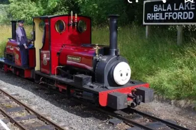a small red train on the tracks with a person on it at Cosy Minffordd Let - Llanuwchllyn near, Bala LL23 in Bala