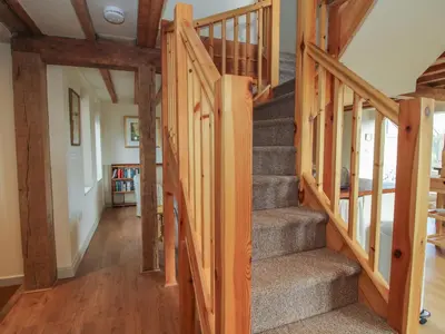 a staircase in a house with wooden beams at Brynlikky Cottage in Bucknell