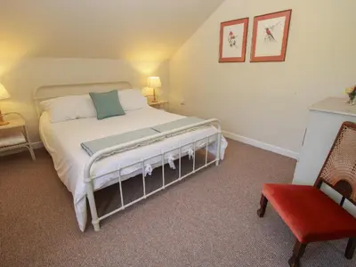 a bedroom with a bed and a red chair at Brynlikky Cottage in Bucknell