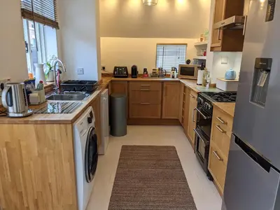 a kitchen with wooden cabinets and a washer and dryer at Luxury townhouse in town centre, views, river walk, Free Parking in Shrewsbury