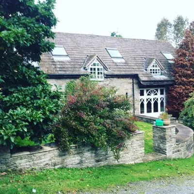 a house with a stone wall in the yard at The Hillis Farmhouse - 6 Bed - Sleeps 11 - Pets in Brecon