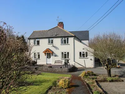 a white house with a bench in front of it at Belmont Bridge in Oswestry