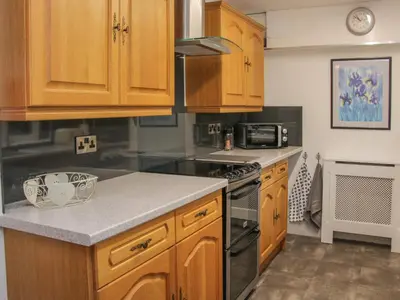 a kitchen with wooden cabinets and a stove top oven at Belmont Bridge in Oswestry