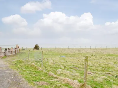a fence in the middle of a field at Plas Bach in Llanon