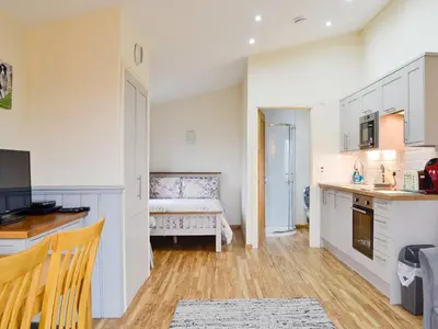 a kitchen with white cabinets and a bench in a room at Ty Nant - Uk32239 in Lower Chapel