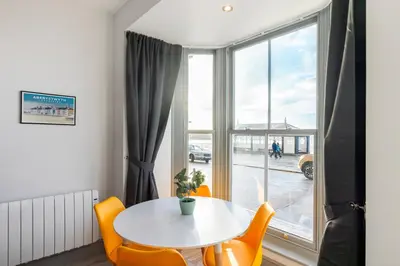 a white table and chairs in a room with a window at New central seafront apartment- stunning sea views in Aberystwyth