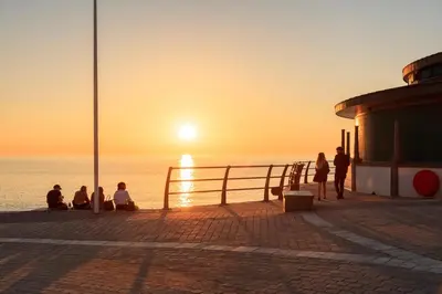 a group of people sitting on a pier watching the sunset at New central seafront apartment- stunning sea views in Aberystwyth
