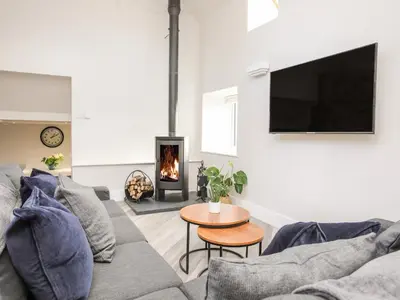 a living room with a couch and a fire place at Drovers Barn in Corwen