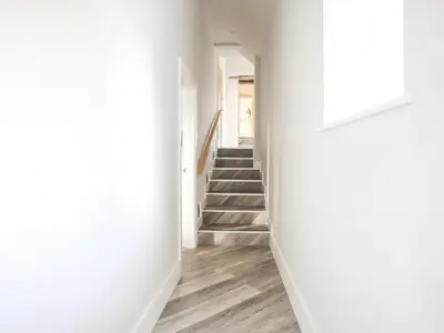 a hallway with white walls and stairs with a door at Drovers Barn in Corwen
