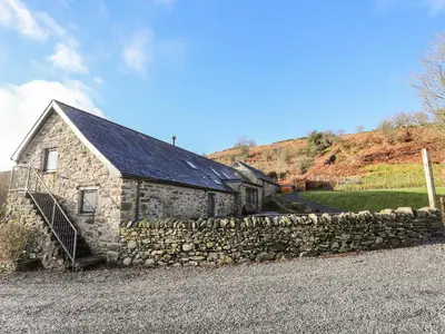 a stone house with a stone wall in front of it at Drovers Barn in Corwen
