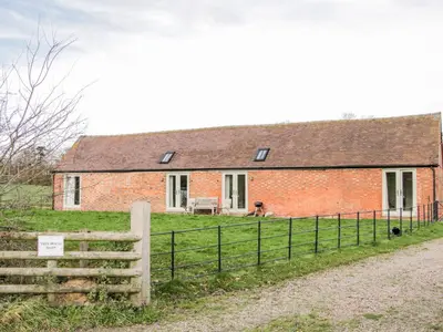 a brick house with a fence in front of it at Treehouse Barn at Pitchford Estate in Shrewsbury