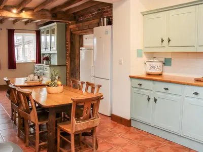 a kitchen with a wooden table and a refrigerator at Stockbatch Granary at Pitchford Estate in Shrewsbury