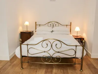 a bed in a room with two lamps on tables at Stockbatch Granary at Pitchford Estate in Shrewsbury