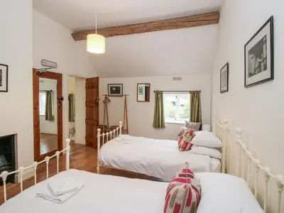 a bedroom with three beds and a fireplace at Stockbatch Granary at Pitchford Estate in Shrewsbury