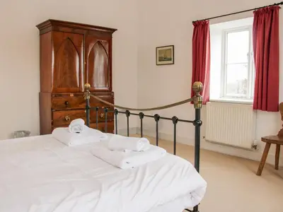 a bedroom with a bed with a wooden headboard and red curtains at Stockbatch Granary at Pitchford Estate in Shrewsbury