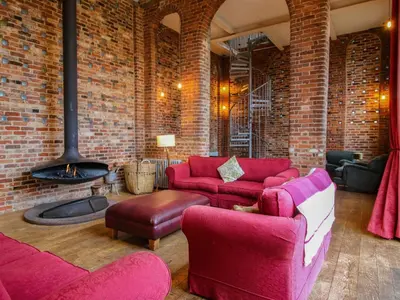 a living room with red couches and a brick wall at Windy Mundy Farm at Pitchford Estate in Shrewsbury