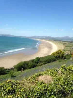 a view of a sandy beach with the ocean at Bryn Derw in Talsarnau