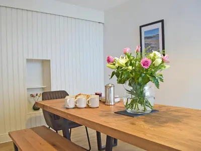 a wooden table with a vase of flowers on it at Bristol House in New Quay