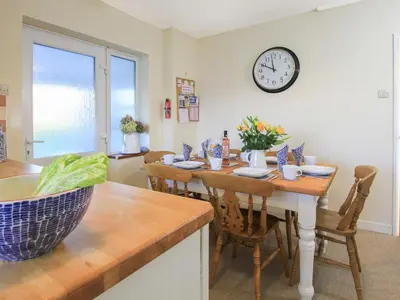 a dining room with a table and a clock on the wall at Garnedd Lwyd in Harlech
