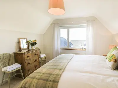 a bedroom with a large bed and a window at Garnedd Lwyd in Harlech