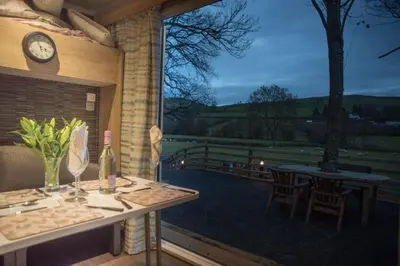 a balcony with a table and chairs and a clock at The Fox Den in Rhayader
