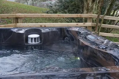 a black pool of water in front of a wooden fence at The Fox Den in Rhayader