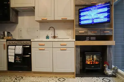 a kitchen with a tv and a fireplace with a fire at Woodland Escape in Nantmel