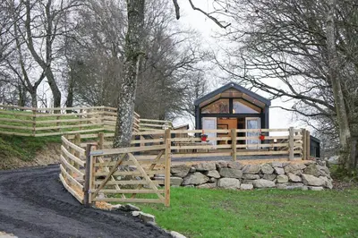 a wooden fence and a gazebo in a field at Woodland Escape in Nantmel
