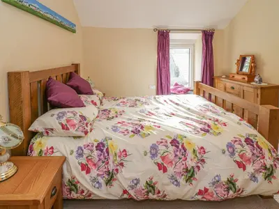 a bedroom with a bed with a floral bedspread at 1 Rhys Terrace in Pennal
