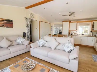 a living room with two couches and a kitchen at McAuliffe Lodge in Borth