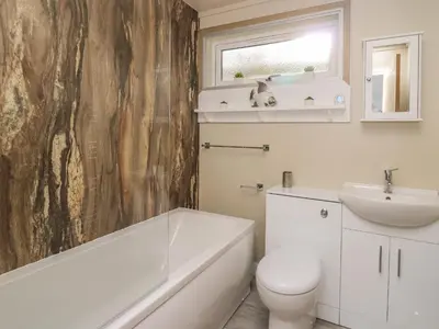 a bathroom with a white tub and a sink and a toilet at McAuliffe Lodge in Borth