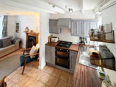 a kitchen with stainless steel appliances and a living room at Driftwood in Aberdyfi