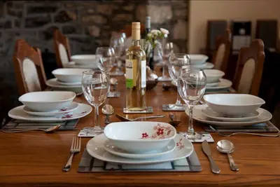 a table with plates and glasses and a bottle of wine at Merlin Cottages in Llandovery