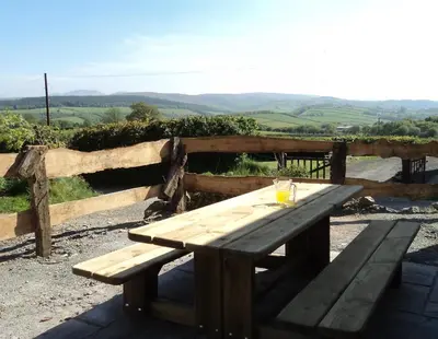 a wooden picnic table in front of a wooden fence at Merlin Cottages in Llandovery