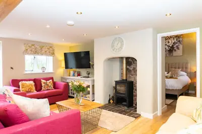 a living room with a red couch and a fireplace at The Patches in Shrewsbury