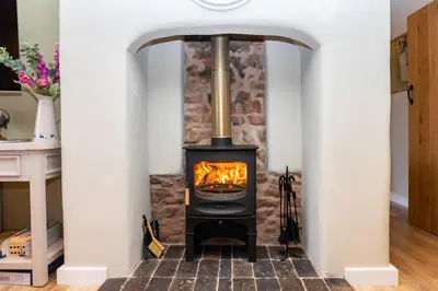 a stove in a living room with a stone wall at The Patches in Shrewsbury