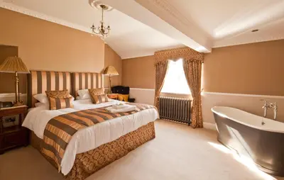 a bedroom with a bed and a bath tub next to a window at Bettws Hall Accommodation in Newtown