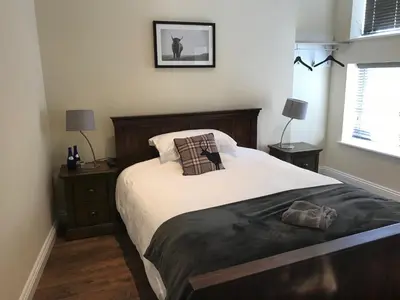 a bedroom with a large bed and two night stands at Bettws Hall Accommodation in Newtown