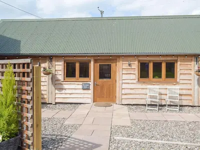 a wooden cabin with a green roof and two chairs at Badgers Den - Uk32084 in Dorstone