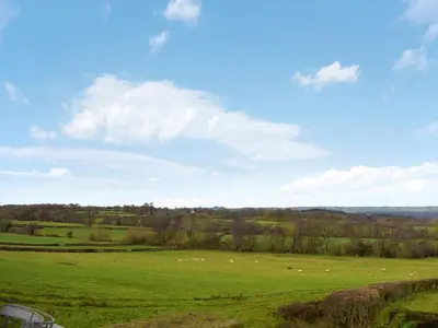 a green field with sheep grazing in the distance at Badgers Den - Uk32084 in Dorstone