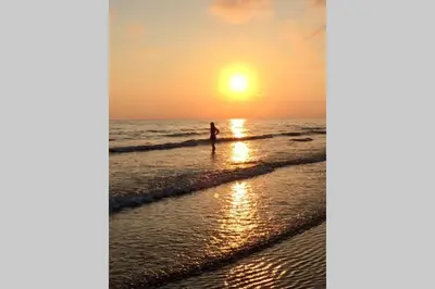 a person standing on the beach at sunset at Lle Mary - Beautiful views, Hot tub, Secluded, Dog Welcome, Barmouth in Llanddwywe