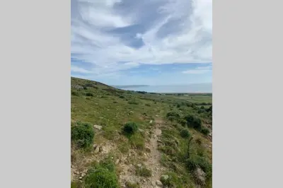 a dirt road on a grassy hill with a cloudy sky at Lle Mary - Beautiful views, Hot tub, Secluded, Dog Welcome, Barmouth in Llanddwywe