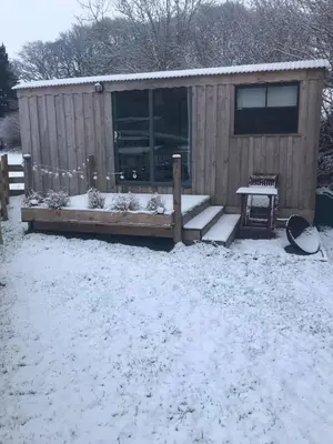 a wooden cabin with snow on the ground at Cefn Crib Cabins in Machynlleth