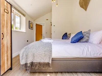 a bedroom with a large white bed with blue pillows at Barn Owls Rest in Clyro