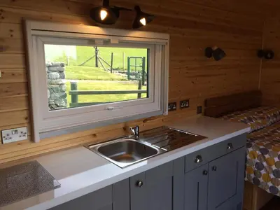 a kitchen with a sink and a window in a cabin at Cwt y Bugail in Barmouth