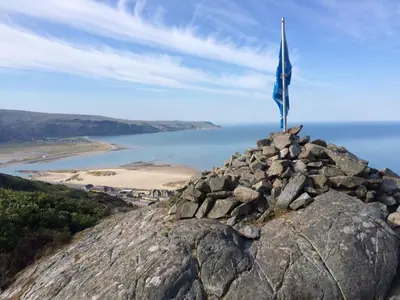 a flag on the top of a rock with a view at Cwt y Bugail in Barmouth