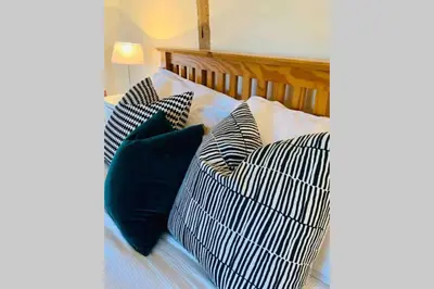 a bed with black and white pillows on it at Upper Heath Farm - Stable Cottage Ludlow in Craven Arms
